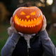 A girl with Halloween pumpkin in front of her head